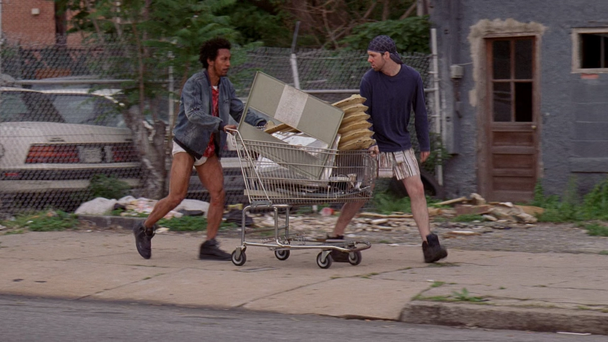 Image of Bubbles and Johnny pushing a cart filled with junk metals. Both of them are not wearing any pants.