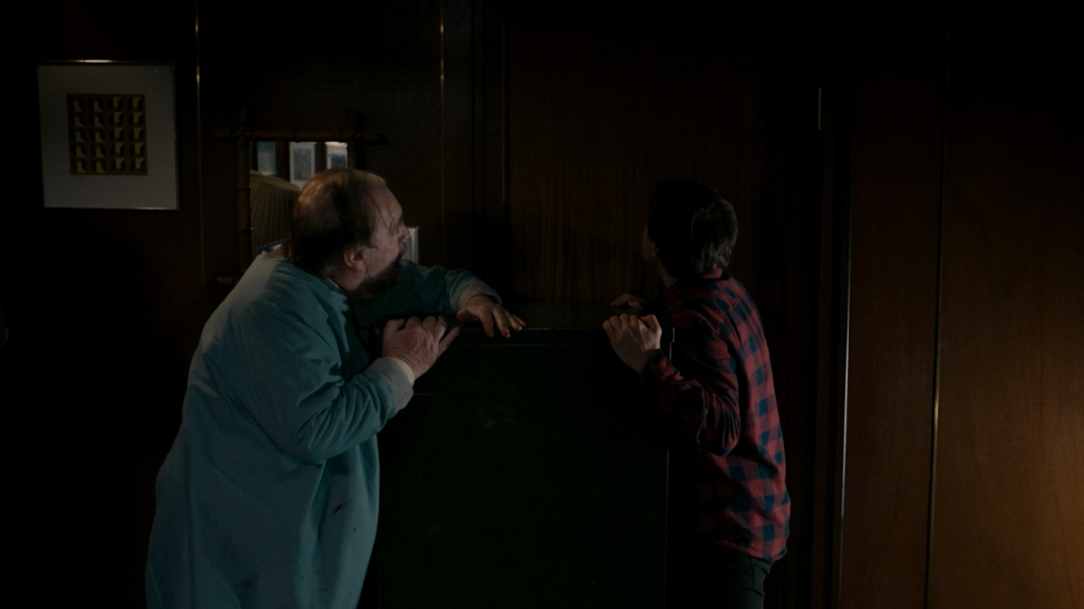 Austin and Tommy are blocking the office door using a file cabinet.