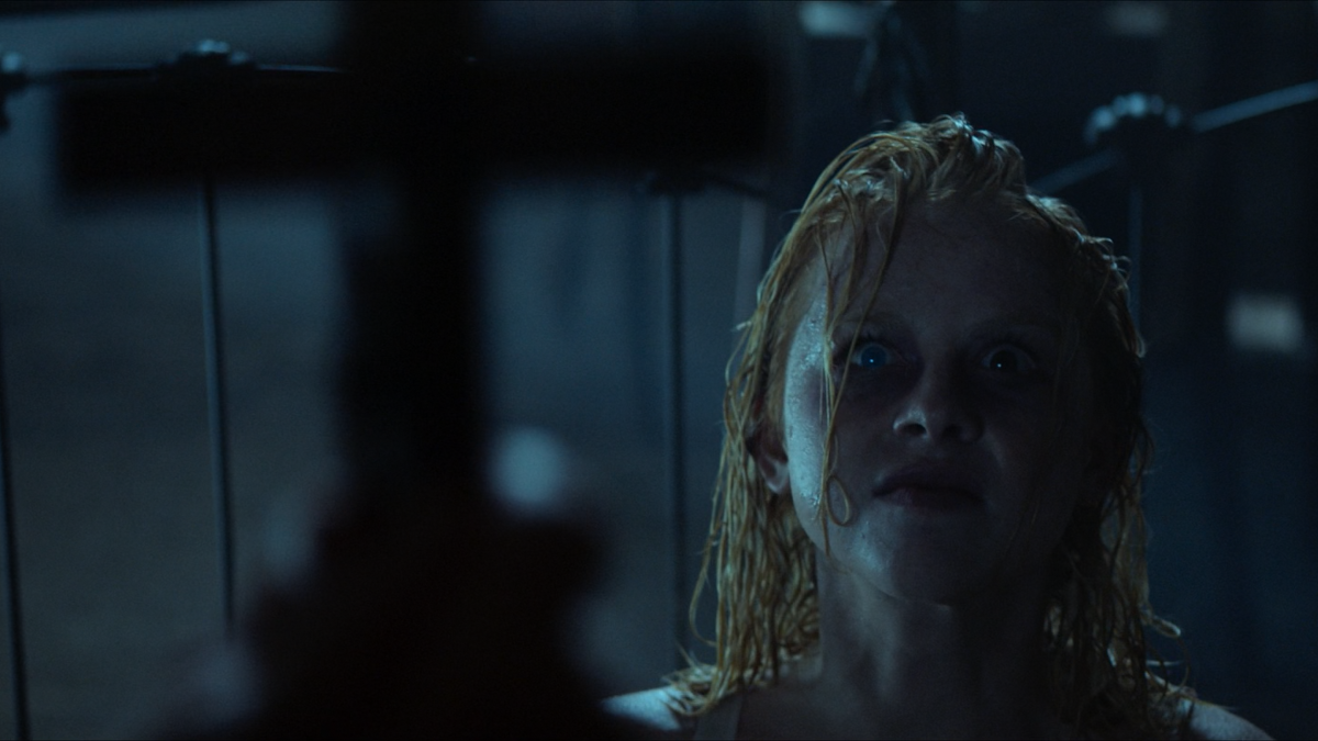 A possessed girl is looking at a cross.