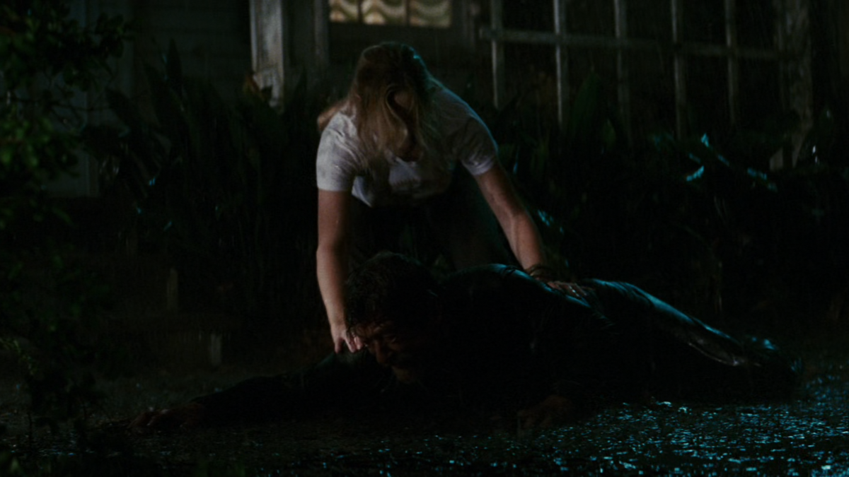 Old man Ben is crawling on a muddy ground. Young woman Caroline is trying to stop him.